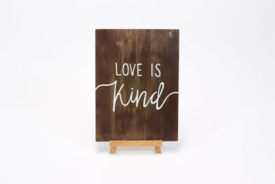 Dark wooden sign- "love is.........."